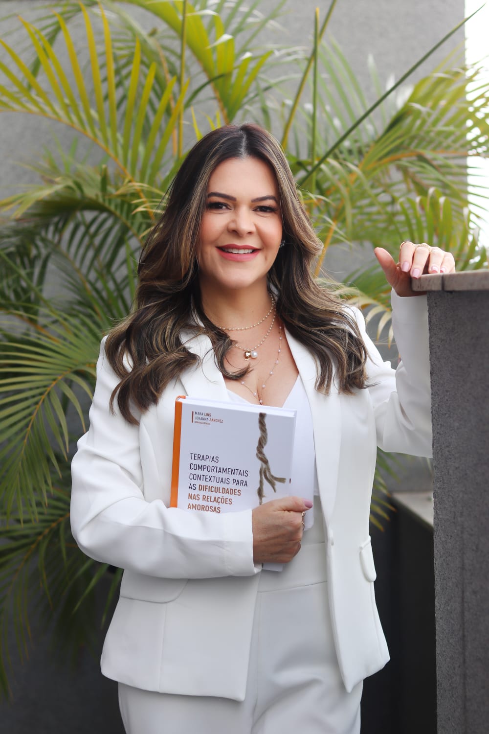 Almira Marques em pé, segurando um livro sobre relações amorosas